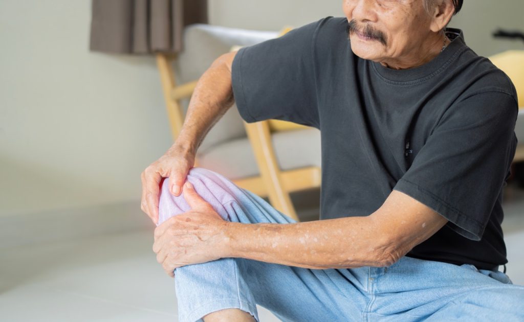 Close-up of a person holding their leg due to chronic knee inflammation and joint stiffness.