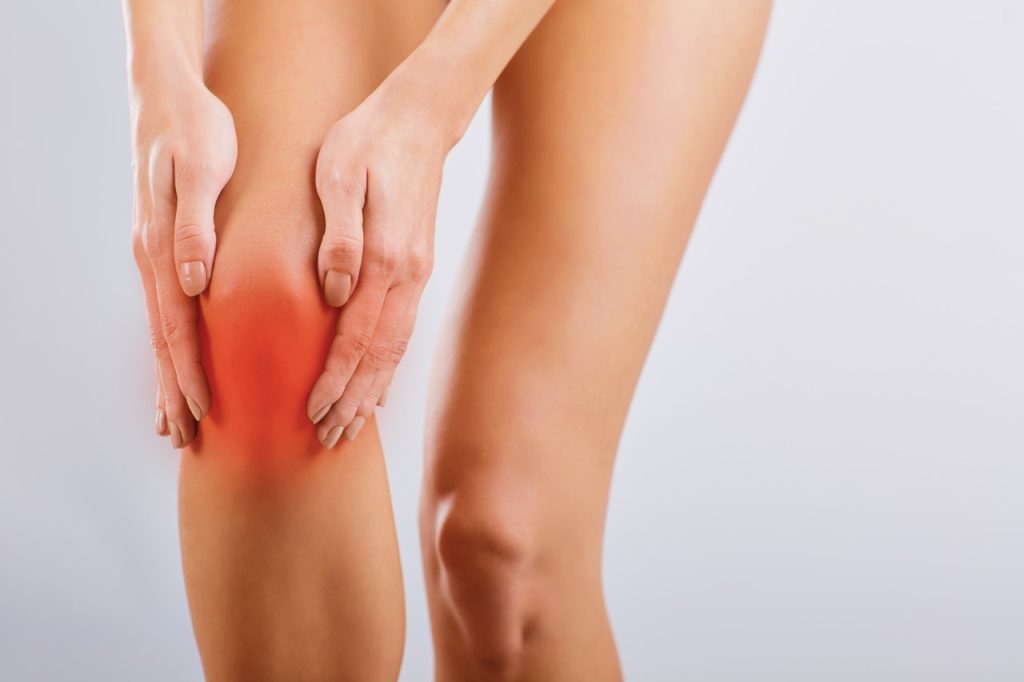 Close-up of a woman holding an inflamed knee due to knee arthritis without severe pain.