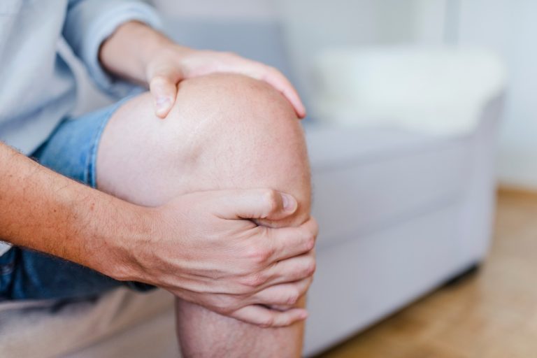 Close-up of a person holding their painful knee during a knee arthritis flare-up.