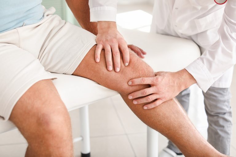 Physician assessing knee pain during a medical consultation with a senior patient.