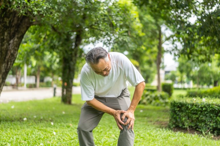 Older man experiencing knee pain while walking