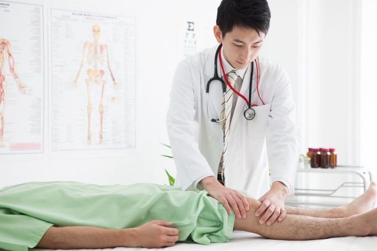 Doctor examining a patient's painful, weak knee during a medical consultation