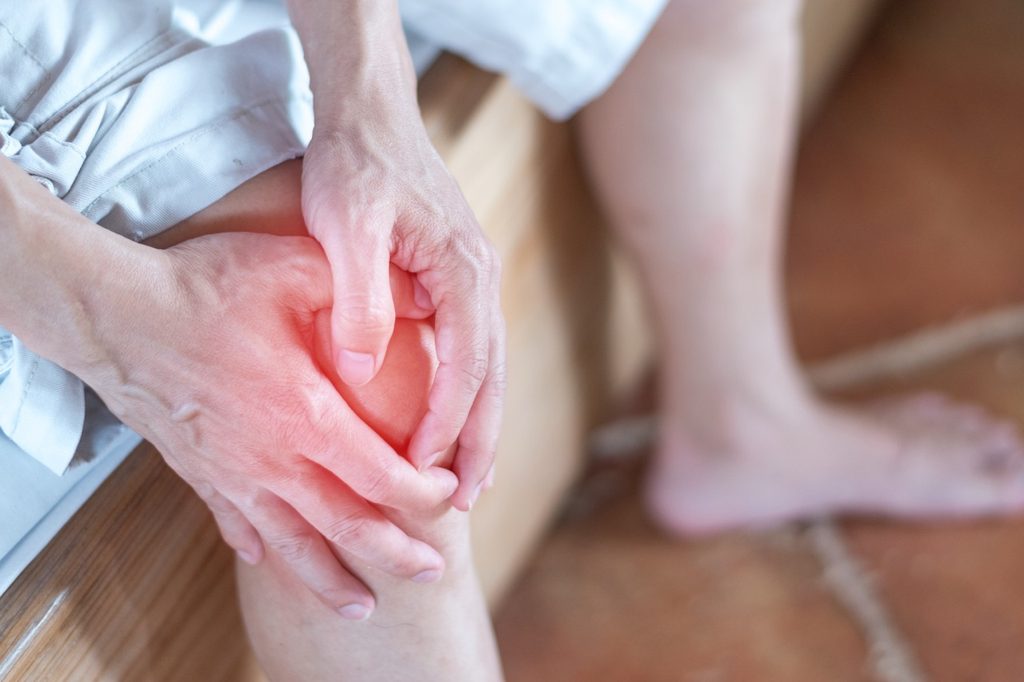 Close-up of a person holding their painful, inflamed knee joint