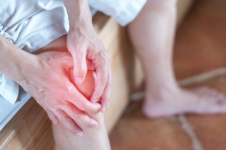 Close-up of a person holding their painful, inflamed knee joint