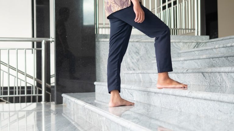 Man walking on stairs with knee pain related to knee osteoarthritis symptoms